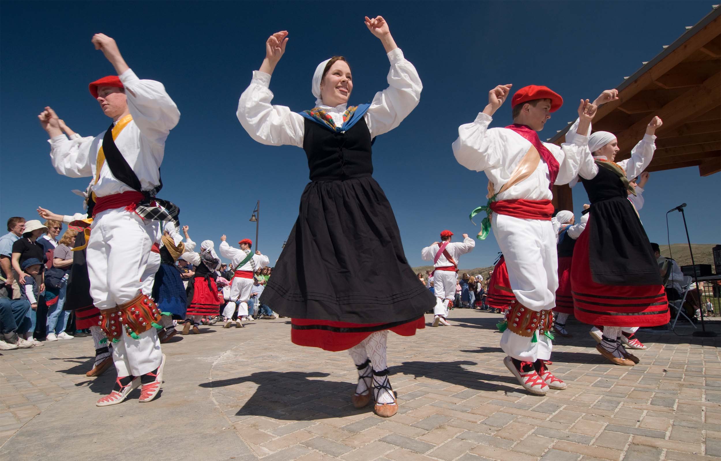 A group of people dancing in traditional Basque outfits in front of an audience at the Jaialdi Festival.