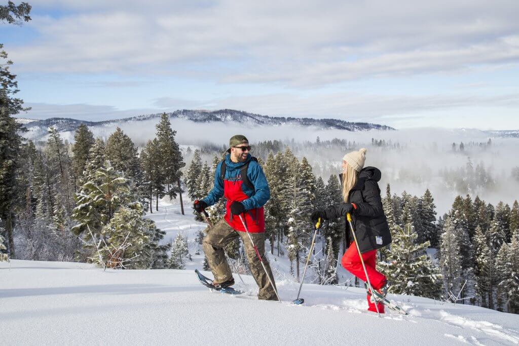 Two people smile at eachother as they snowshoe near Idaho City.